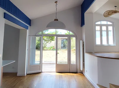 Salon lumineux avec sol en bois, portes-fenêtres donnant sur jardin et accents bleus à l'Ile de Ré en Charente-Maritime 17