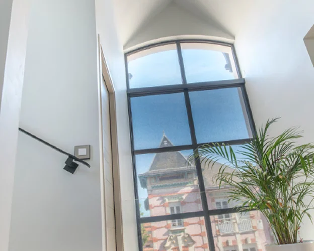 Grande fenêtre en arc avec une plante et un bâtiment rose à l'extérieur à l'Ile de Ré en Charente-Maritime 17