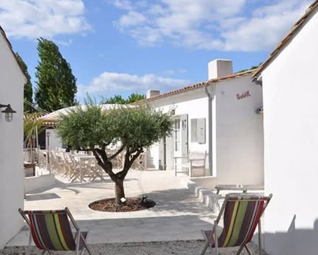 Cour intérieure ensoleillée avec arbre, chaises longues et bâtiments blancs à l'Ile de Ré en Charente-Maritime 17
