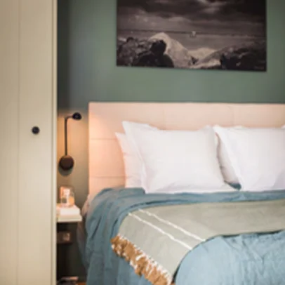 Chambre confortable avec lit fait, art mural abstrait et lampe de lecture.