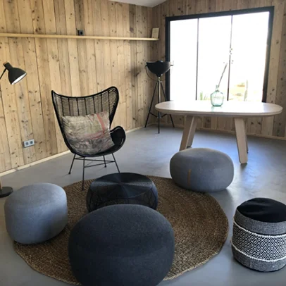 Salon moderne en bois avec des poufs, une table et une chaise.