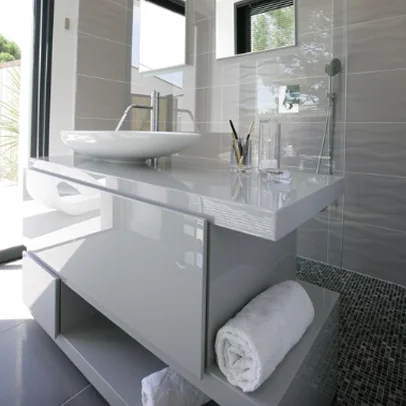 Salle de bain moderne grise avec lavabo vasque, meuble suspendu et douche.