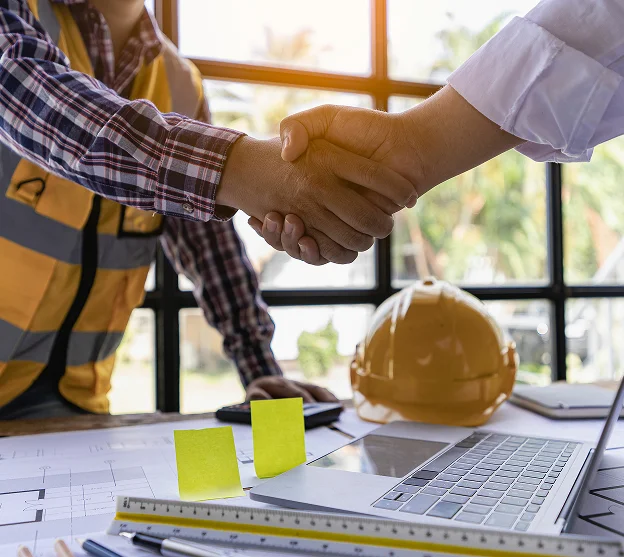 Architecte et ouvrier du bâtiment se serrant la main au-dessus de plans et d'un casque à l'Ile de Ré en Charente-Maritime 17