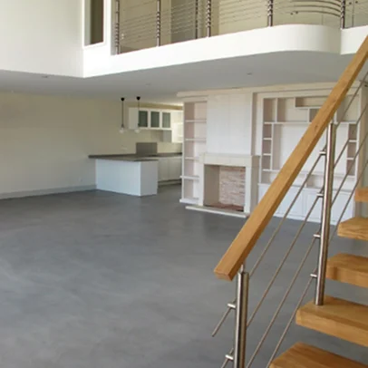 Intérieur moderne et vide avec escalier en bois, balustrade métallique et cuisine ouverte.